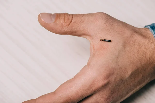 Vista recortada de la mano masculina con microchip en la mesa - foto de stock