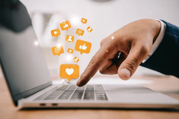 Partial view of businessman typing on laptop at workplace with multimedia icons — Stock Photo