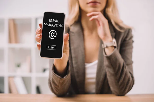 Abgeschnittene Ansicht einer Geschäftsfrau, die Smartphone mit E-Mail-Marketing-Ikone präsentiert — Stockfoto