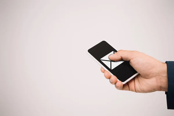 Vista recortada del hombre de negocios utilizando el teléfono inteligente con el icono de correo electrónico aislado en gris - foto de stock