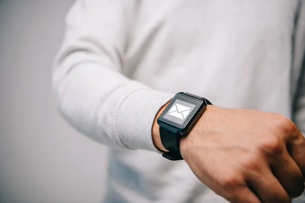 Ausgeschnittene Ansicht eines Mannes mit Smartwatch mit E-Mail-Symbol — Stockfoto