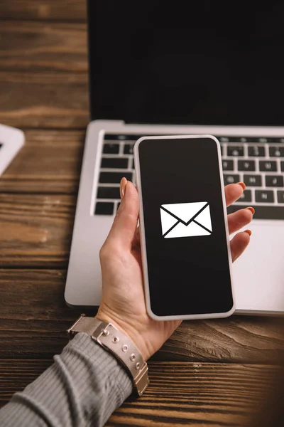 Vista recortada de la mujer de negocios sosteniendo teléfono inteligente con el icono de correo electrónico — Stock Photo