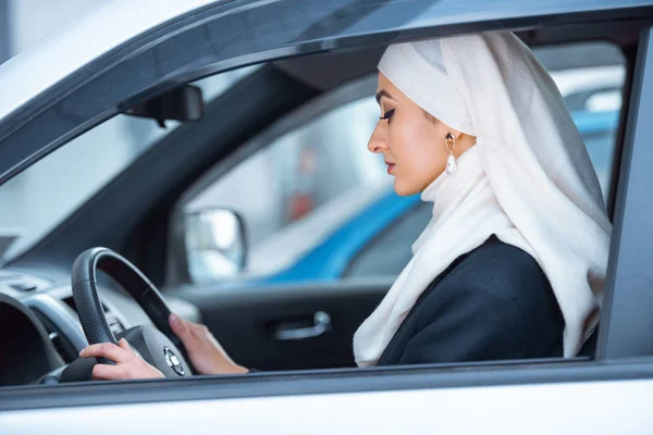 Vista lateral da bela jovem muçulmana carro de condução — Fotografia de Stock