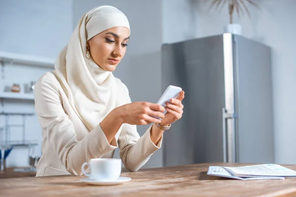Красивая молодая мусульманка с помощью смартфона дома — стоковое фото