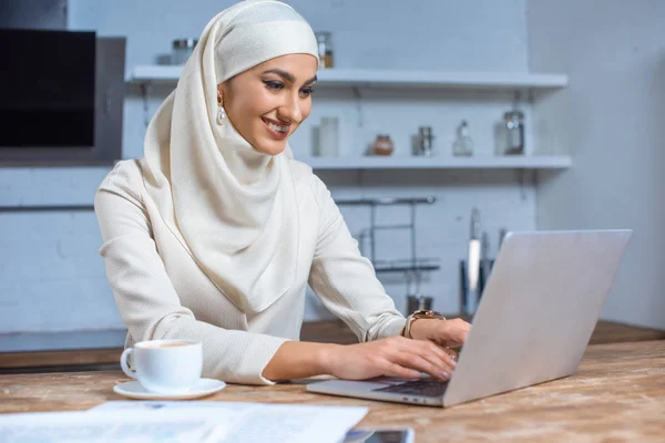 Bella sorridente giovane donna musulmana utilizzando il computer portatile a casa — Foto stock