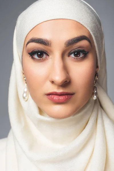 Close-up portrait of beautiful young muslim woman looking at camera isolated on grey — Stock Photo