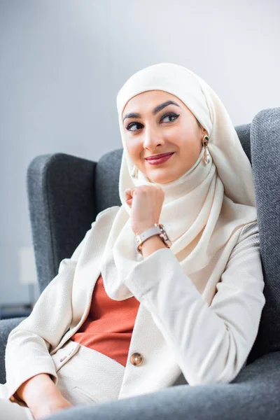 Schöne junge muslimische Frau, die zu Hause lächelt und wegschaut — Stockfoto