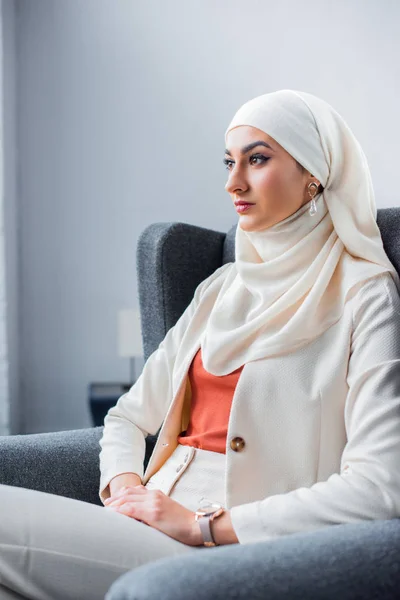 Chère jeune femme musulmane assise sur la chaise et regardant loin — Photo de stock