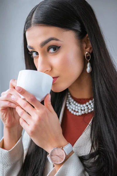 Belle jeune femme boire du café et regarder la caméra — Photo de stock