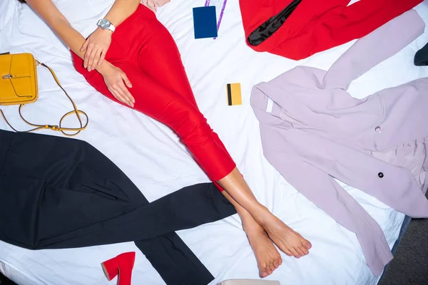 Sección baja de la mujer joven acostada en la cama con ropa elegante y tarjeta de crédito - foto de stock