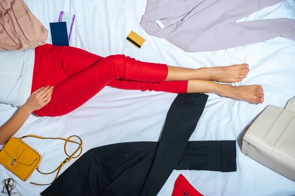 Cropped shot of young woman lying on bed with stylish clothes and credit card — Stock Photo