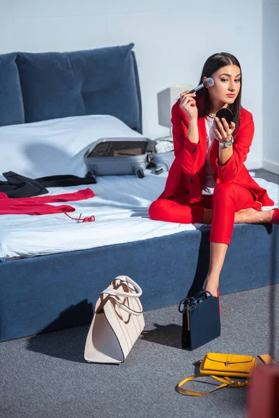 Schöne stilvolle junge Frau sitzt auf dem Bett und schminkt — Stockfoto