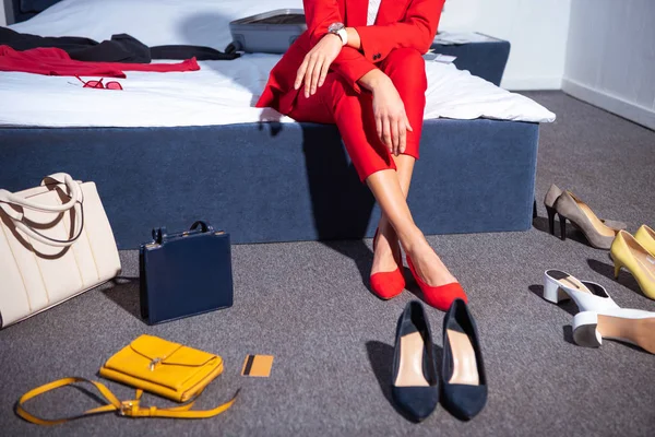 Plan recadré de fille en costume rouge élégant et chaussures assis sur le lit — Photo de stock