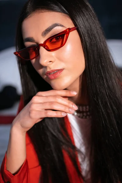 Porträt einer schönen jungen Frau mit roter Sonnenbrille, die in die Kamera blickt — Stockfoto