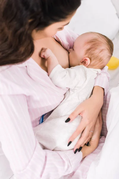 Jeune mère allaitant petit bébé à la maison — Photo de stock