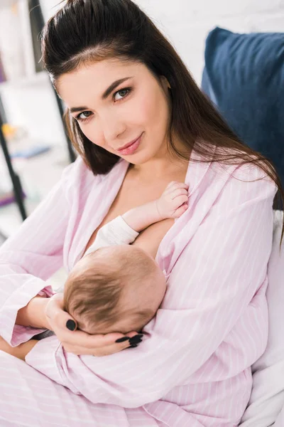 Portrait of young mother breastfeeding little baby at home — Stock Photo
