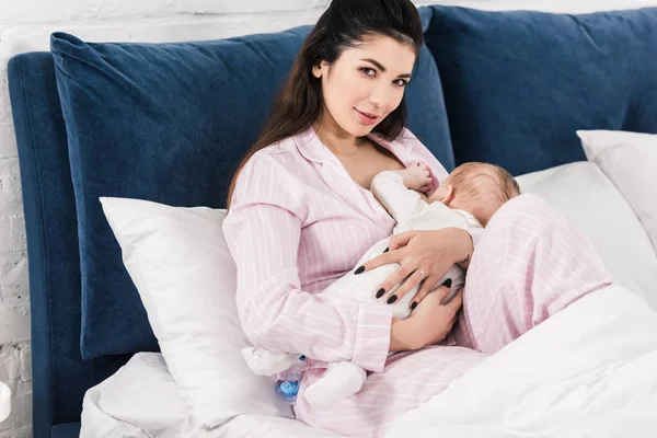 Retrato de jovem mãe amamentando bebê na cama em casa — Fotografia de Stock