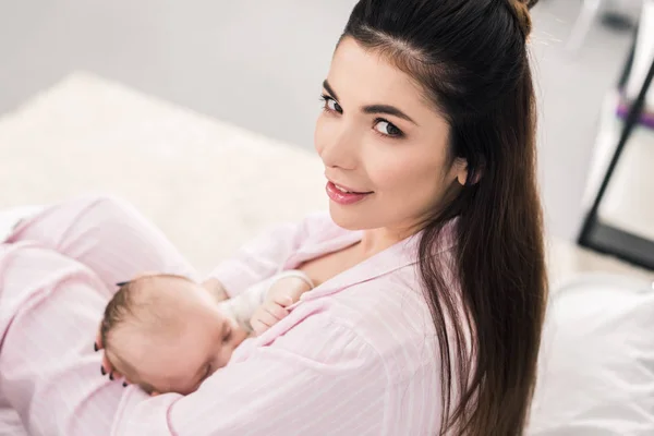 Vue latérale de la jeune mère allaitant petit bébé à la maison — Photo de stock