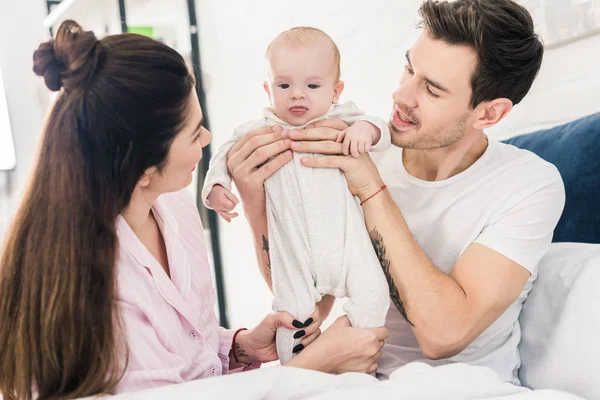 Parents et petit bébé se reposant sur le lit ensemble à la maison — Photo de stock