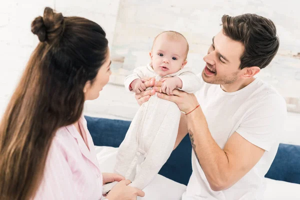 Padres y pequeño bebé descansando en la cama juntos en casa - foto de stock