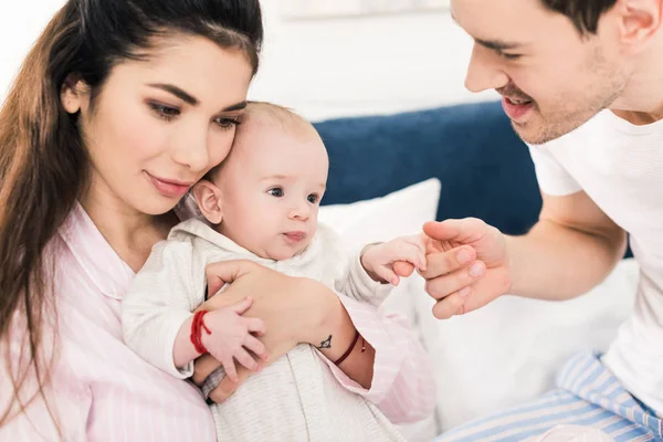 Parents and little baby resting on bed together at home — Stock Photo
