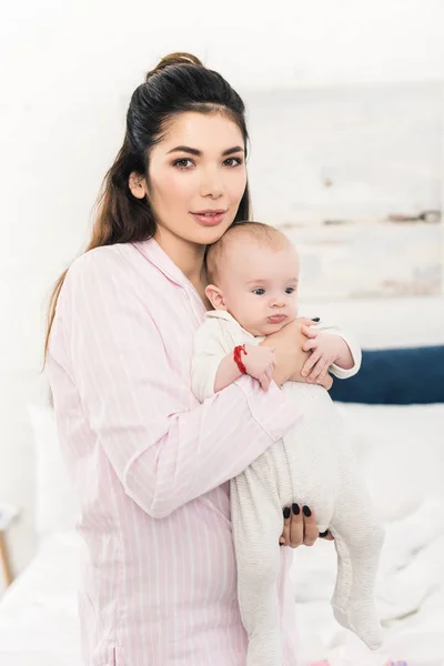 Porträt einer jungen schönen Mutter mit kleinem Baby an der Hand zu Hause — Stockfoto