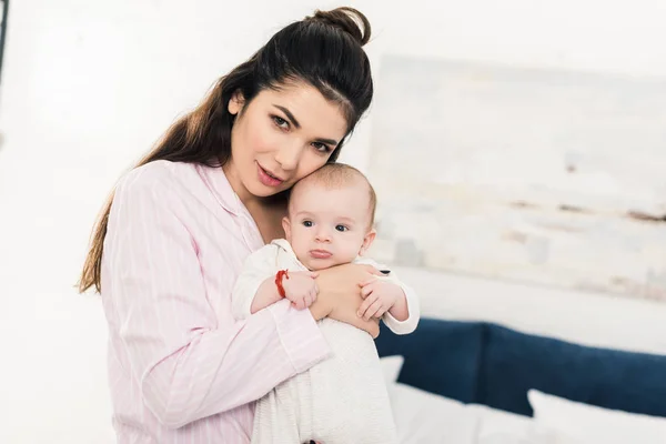 Porträt einer jungen schönen Mutter mit kleinem Baby an der Hand zu Hause — Stockfoto