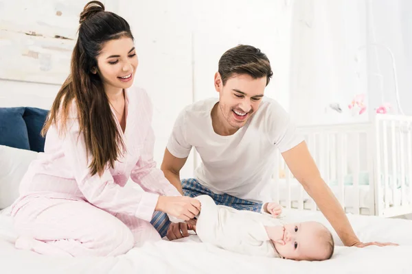 Happy parents resting on bed together with cute baby at home — Stock Photo