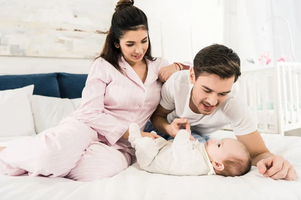 Счастливые родители отдыхают на кровати вместе с милым ребенком дома — стоковое фото