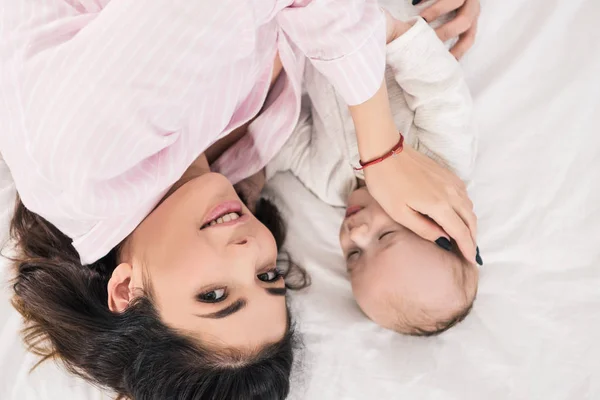 Vista aérea de la madre y el pequeño hijo acostados en la cama juntos - foto de stock