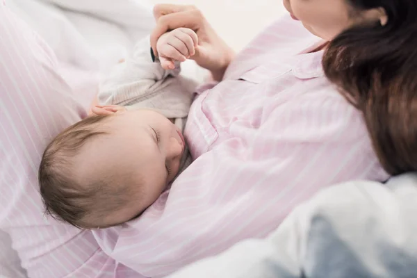 Teilansicht des niedlichen Babys, das auf den Händen der Mutter schläft — Stockfoto