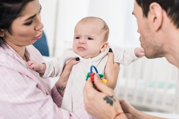Parents looking at emotional baby in hands at home — Stock Photo