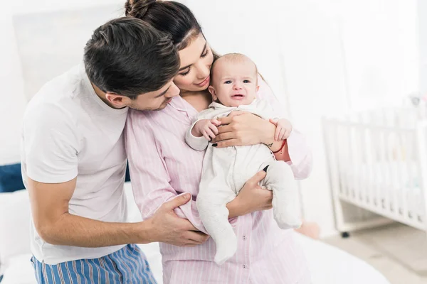 Porträt eines Mannes, der Frau mit kleinem Sohn an Händen zu Hause umarmt — Stockfoto