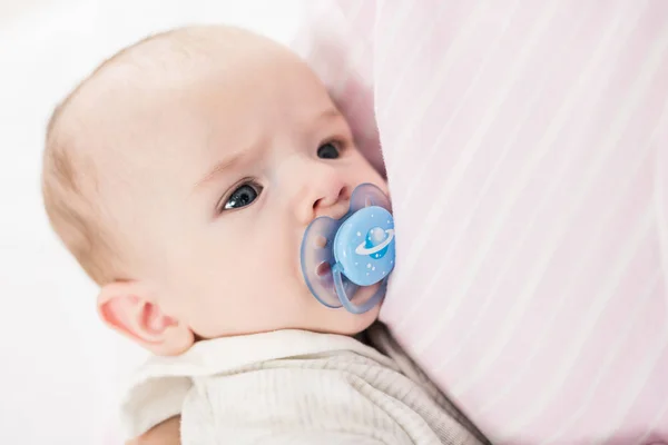 Partial view of little baby with pacifier on mothers hands — Stock Photo