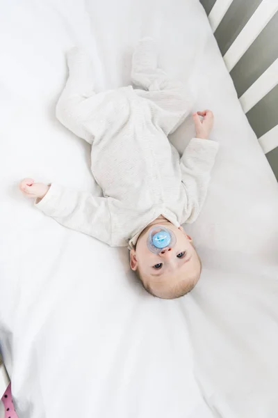 Vista aérea del pequeño bebé con chupete acostado en la cuna — Stock Photo