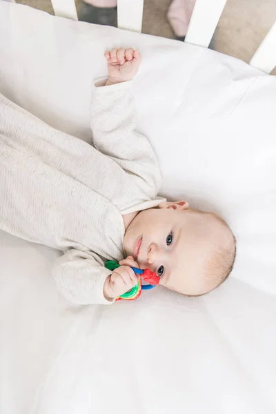 Overhead view of adorable baby with toy in crib — Stock Photo