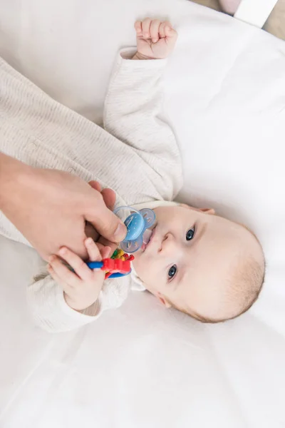 Cropped shot of father giving pacifier to little son in crib — Stock Photo