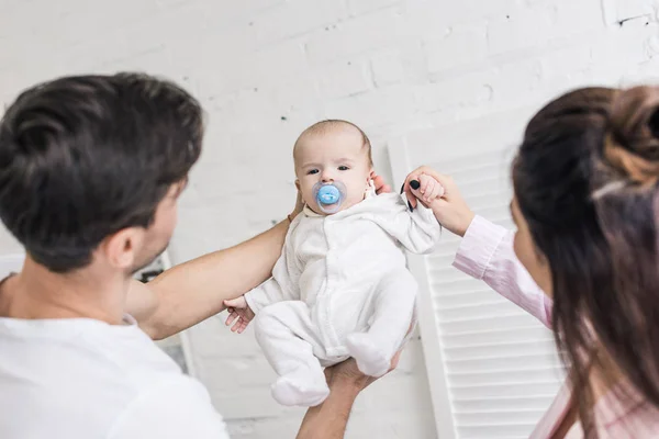 Retrato de padres jóvenes y lindo bebé pequeño con chupete en casa - foto de stock