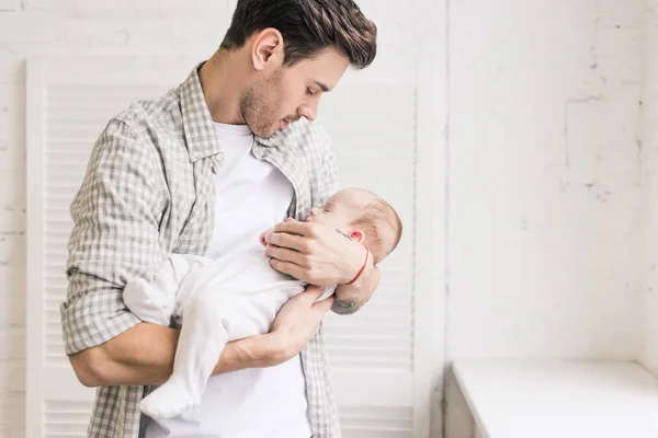 Ritratto di giovane uomo che tiene adorabile bambino addormentato in mano — Foto stock