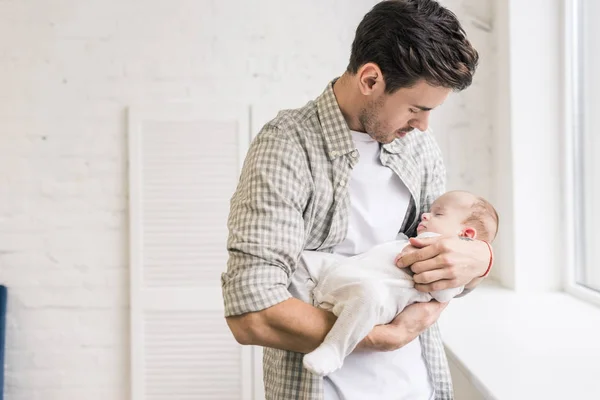 Portrait of young man holding adorable sleeping baby in hands — Stock Photo