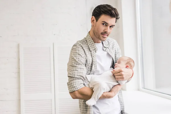 Retrato de un joven con un adorable bebé dormido en las manos - foto de stock