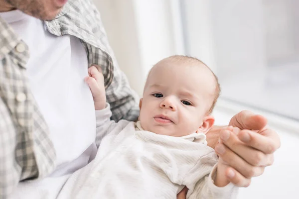 Vista parcial del padre sosteniendo a su pequeño hijo en las manos - foto de stock