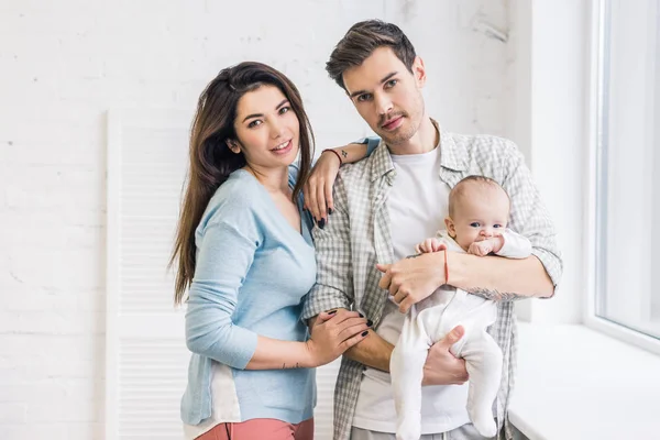 Retrato de padres jóvenes con bebé en casa - foto de stock