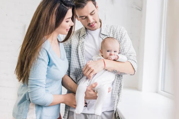 Retrato de padres jóvenes con bebé en casa - foto de stock