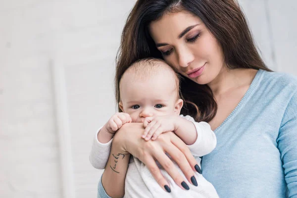 Ritratto di giovane madre con piccolo bambino in mano a casa — Foto stock