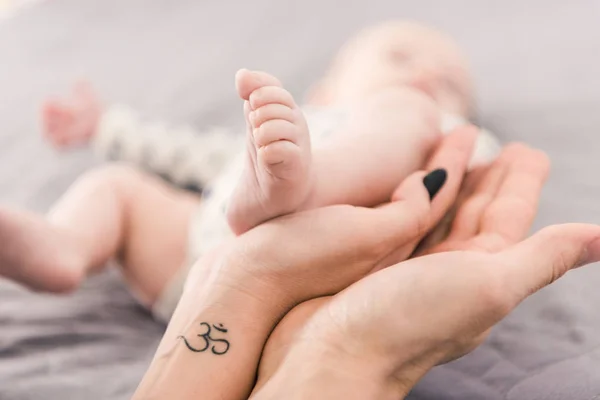 Partial view of mother and father holding babys foot together — Stock Photo