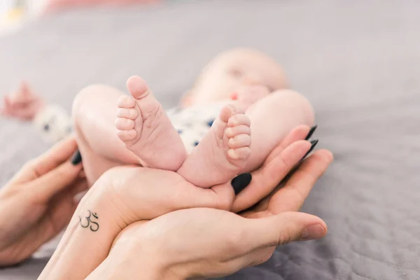 Visión parcial de la madre y el padre sosteniendo pies de bebé juntos - foto de stock