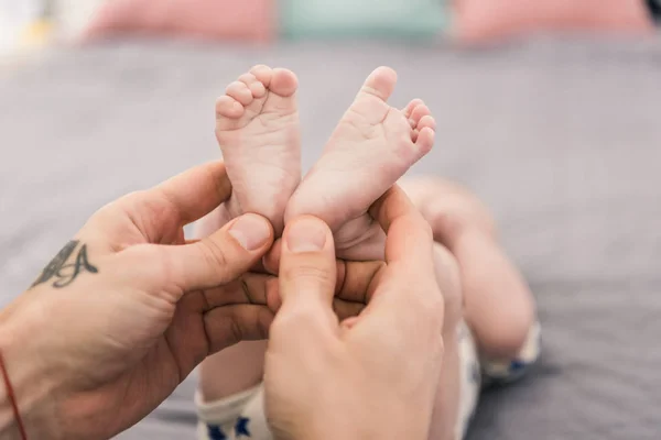 Tiro cortado de pai segurando pequenos filhos pés em mãos — Fotografia de Stock