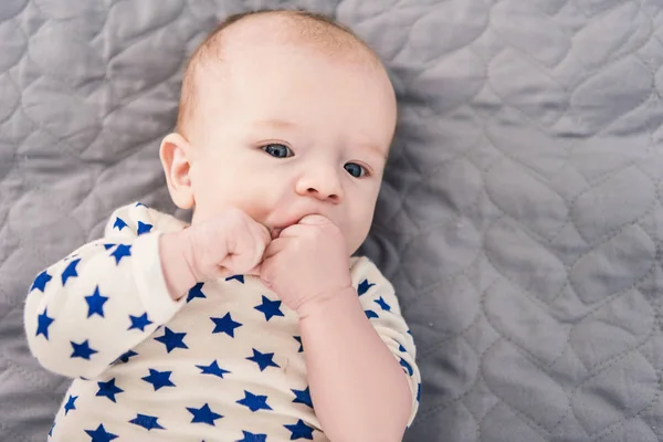 Blick von oben auf ein entzückendes kleines Baby, das auf einer grauen Decke liegt — Stockfoto