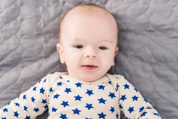 Overhead view of adorable little baby lying on grey blanket — Stock Photo